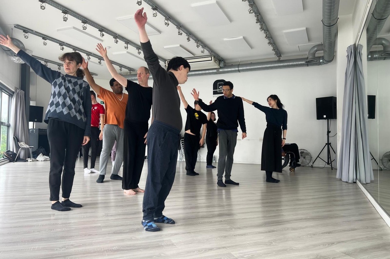 Atelier Entraînement du danseur : un groupe de danseurs, bras levés, dans un studio de danse