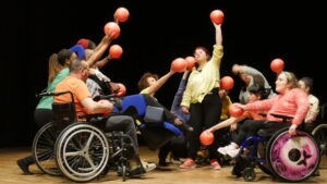 Groupe inclusif avec ballons orange sur scène.