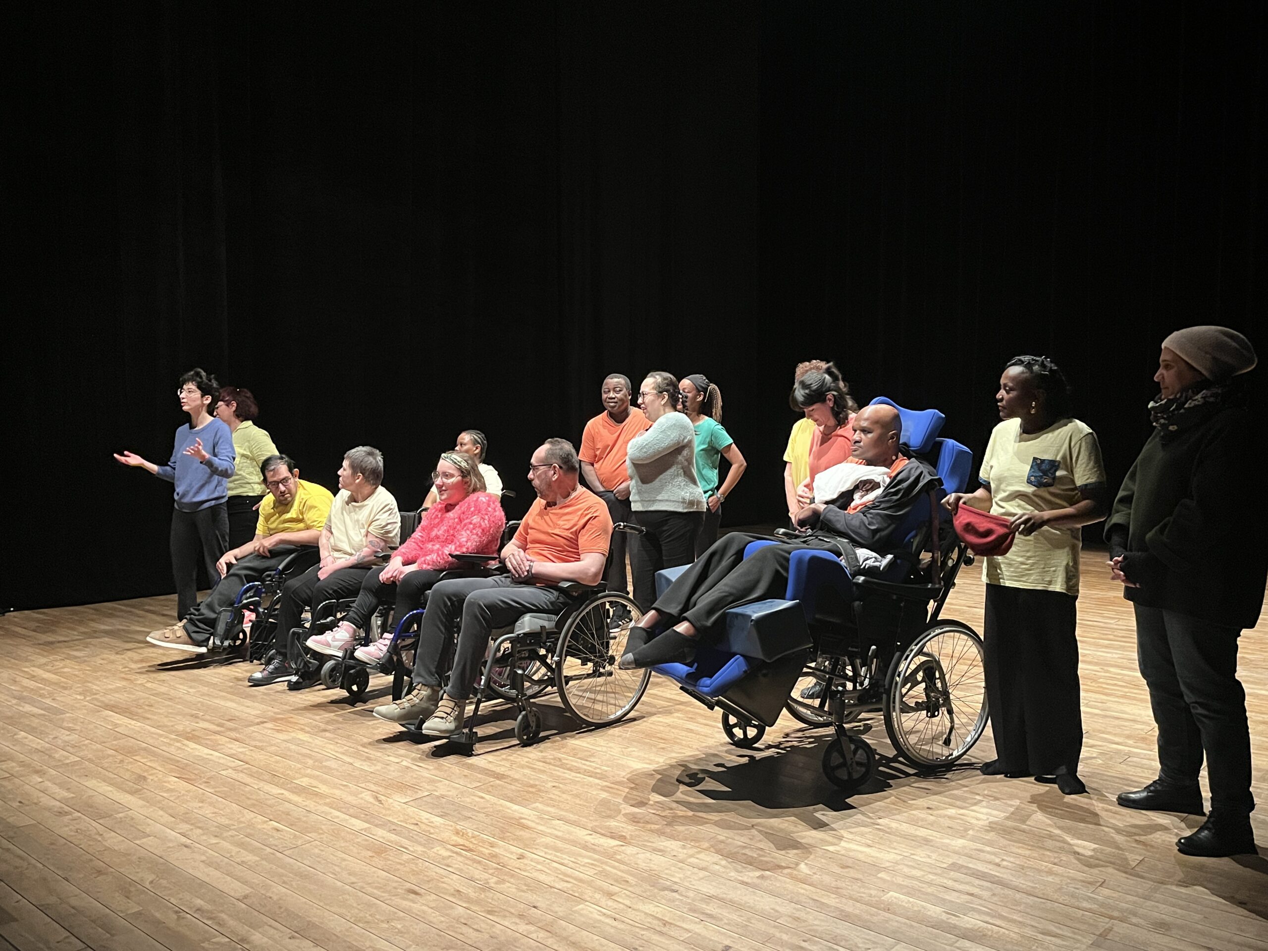Groupe de personnes sur scène, en fauteuils roulants.